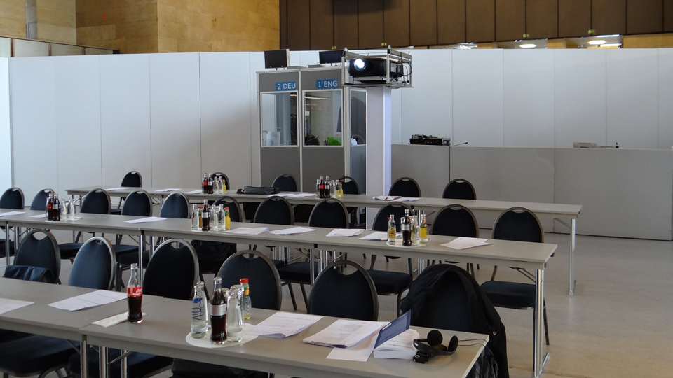 Description: A mobile interpreter booth is placed on a pedestal next to the sound control area, to give the interpreters an unobstructed view of the proceedings at the event.